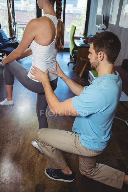 Fisioterapeuta corrigindo posição de paciente do sexo feminino na clínica — Fotografia de Stock