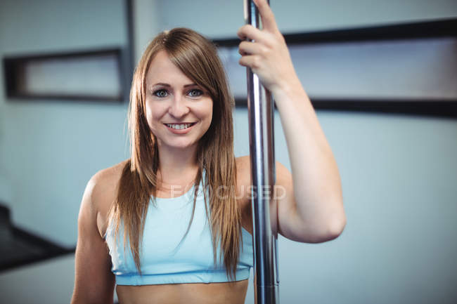 Retrato de una hermosa bailarina de polo sosteniendo poste en un gimnasio - foto de stock