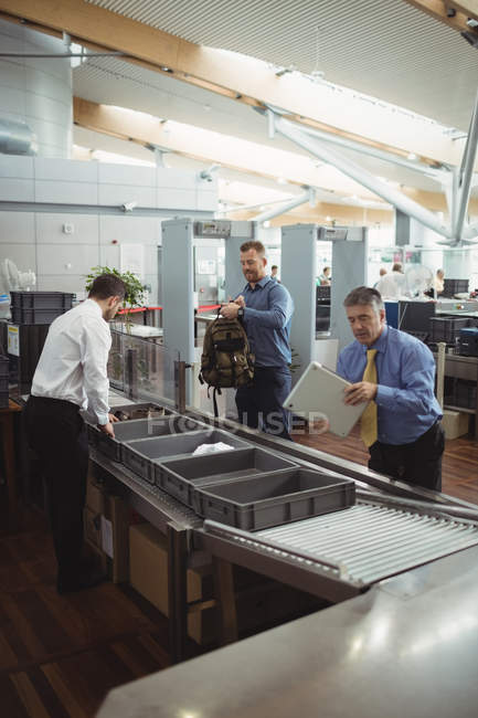 Commuters collecting their bags from the security counter at airport — Stock Photo