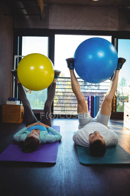 Мужчина и женщина тренируются с мячами для упражнений в клинике — стоковое фото