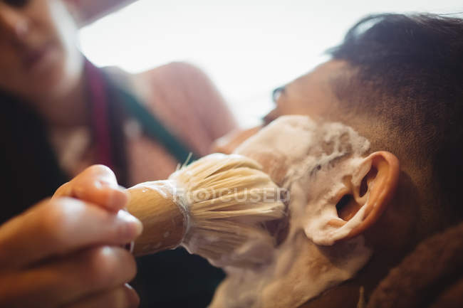 Selective focus of Man getting his beard shaved with shaving brush in barber shop — Stock Photo
