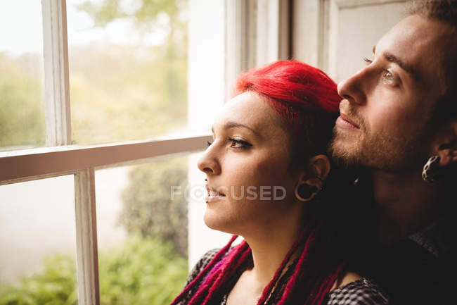 Close-up of young couple looking through window at home — Stock Photo