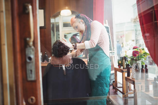 Un hombre afeitándose la barba en una peluquería - foto de stock