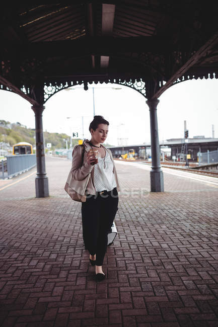 Lunghezza intera della giovane donna con bagagli alla piattaforma della stazione ferroviaria — Foto stock