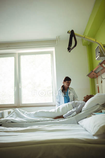Female doctor examining senior man at hospital — Stock Photo