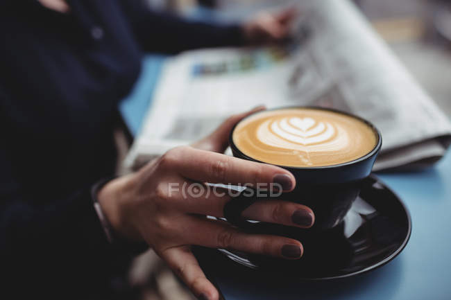 Середина женщины, держащей чашку кофе в кафе — стоковое фото