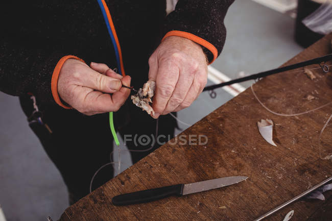 Abgeschnittenes Bild eines Fischers, der Köder auf einem Boot zubereitet — Stockfoto