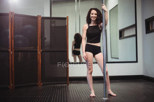 Porträt einer Pole-Tänzerin, die im Fitnessstudio die Stange hält — Stockfoto