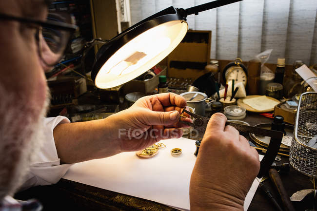 Primer plano del horólogo reparando un reloj en el taller - foto de stock
