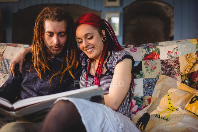 Couple regardant album photo sur le canapé tout en étant assis à la maison — Photo de stock