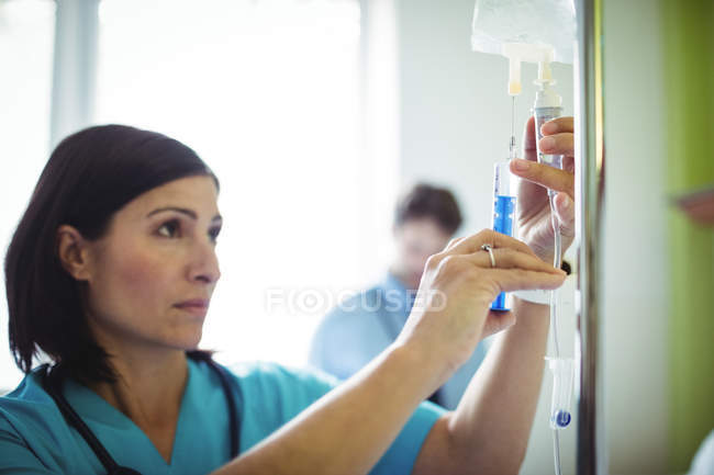Nurse injecting medicine in infusion in hospital — Stock Photo