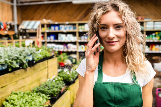 Портрет женщины-флориста, разговаривающей по мобильному телефону в садовом центре — стоковое фото