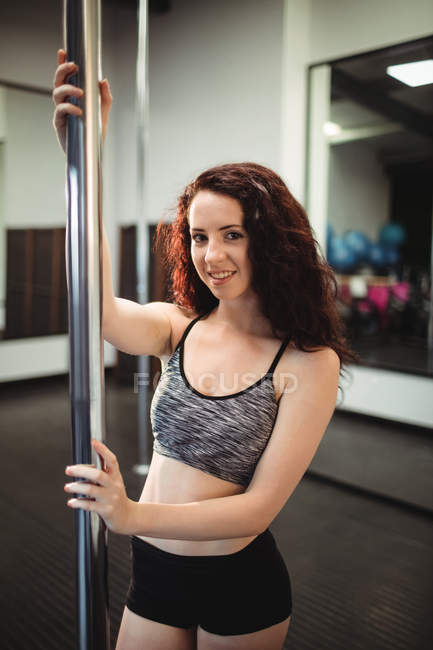 Portrait of pole dancer holding pole in fitness studio — Stock Photo