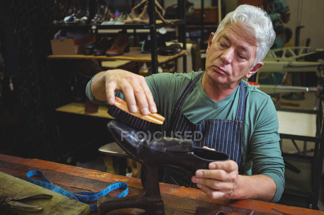 Shoemaker polishing a shoe in workshop — Stock Photo