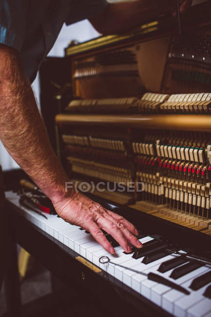 Técnico de piano reparando piano vintage na oficina — Fotografia de Stock