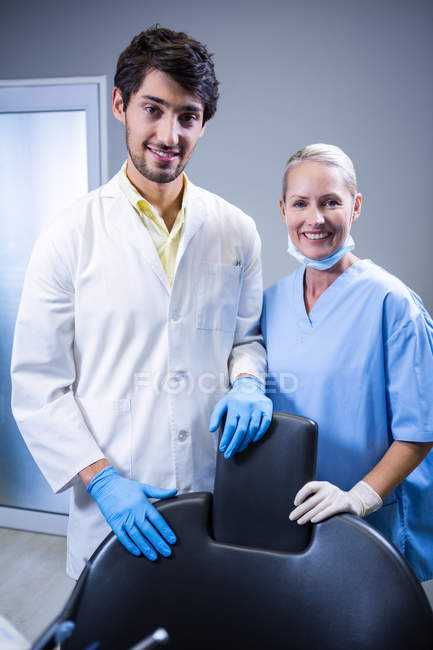 Dentiste et assistante dentaire souriant à la caméra à la clinique dentaire — Photo de stock