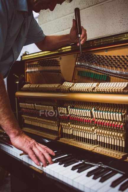 Piano technician repairing vintage piano at workshop — Stock Photo