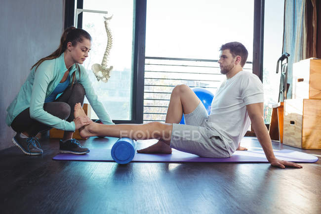 Physiotherapist giving physical therapy to leg of male patient in clinic — Stock Photo
