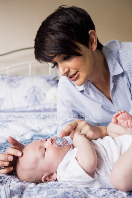 Mère mettre mannequin dans la bouche du bébé à la maison — Photo de stock
