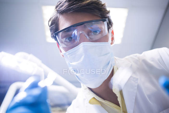 Primo piano del dentista in maschera chirurgica che tiene strumenti dentali in clinica dentale — Foto stock