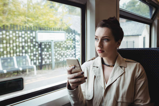 Femme utilisant un téléphone portable pendant qu'elle est assise dans le train — Photo de stock