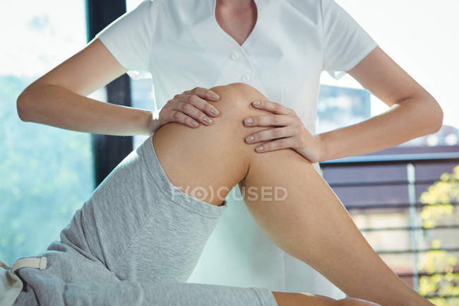 Geschnittenes Bild eines Physiotherapeuten, der dem Knie eines männlichen Patienten in der Klinik physikalische Therapie gewährt — Stockfoto