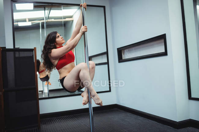 Dançarina de pólo praticando pole dance no estúdio de fitness — Fotografia de Stock