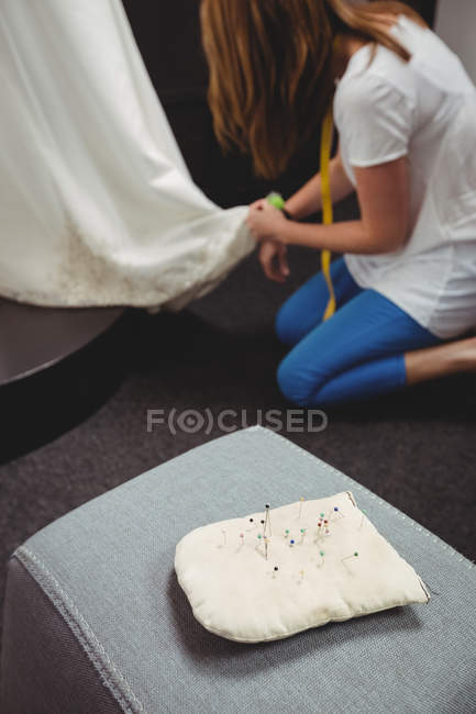 Pincushion on sofa and creative designer working on background in studio — Stock Photo