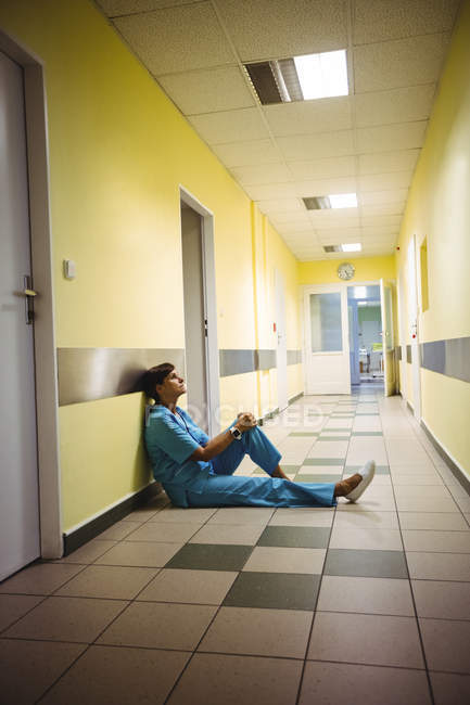Депрессивная медсестра сидит в коридоре больницы — стоковое фото