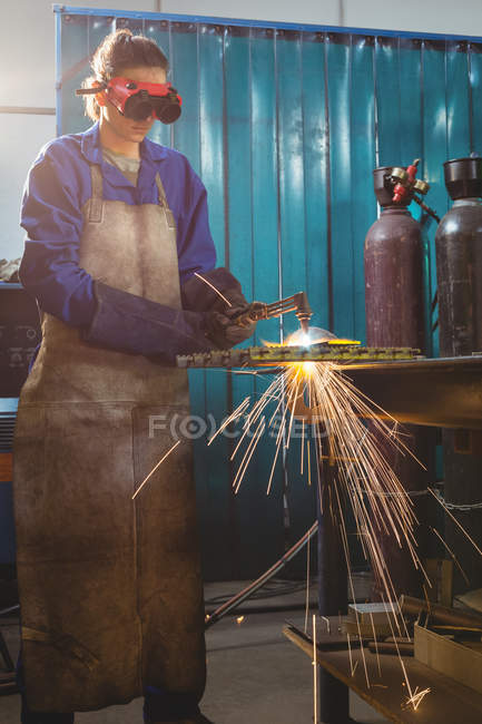 Saldatore donna che lavora su un pezzo di metallo in officina — Foto stock