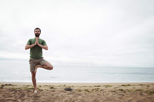 Uomo che esegue yoga sulla spiaggia — Foto stock