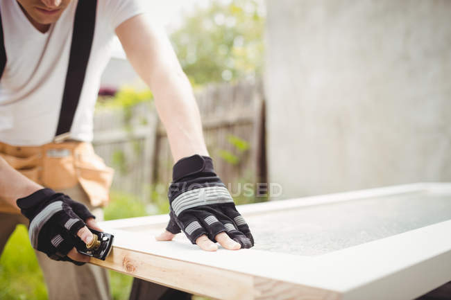 Midsection of carpenter leveling wooden frame with block plane — Stock Photo