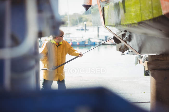 Mann reinigt Boot mit Hochdruckreiniger an sonnigem Tag — Stockfoto
