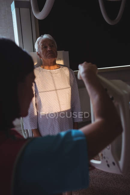 Médico femenino instalando máquina para paciente mayor de rayos X en el hospital - foto de stock