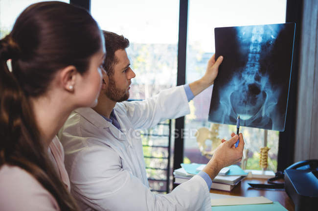 Terapeuta do sexo masculino mostrando raio-X para paciente do sexo feminino na clínica — Fotografia de Stock