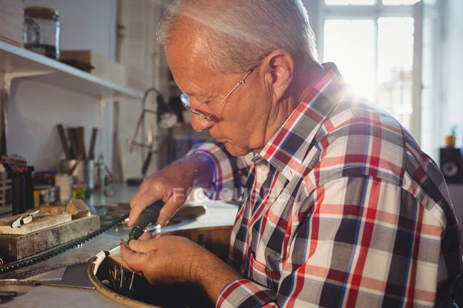 Goldsmith atencioso usando a máquina da peça da mão na oficina — Fotografia de Stock