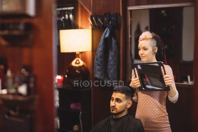 Mulher barbeiro mostrando o homem seu corte de cabelo no espelho na barbearia — Fotografia de Stock