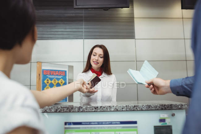 Passengers giving passport to airline check-in attendant at airport check-in counter — Stock Photo