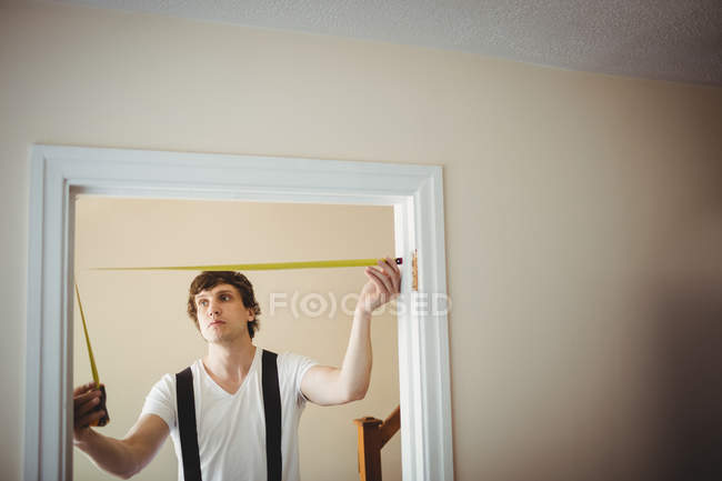 Carpenter measuring door frame at home — Stock Photo