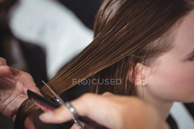 Обрезанный образ женщины, стригущей волосы в салоне — стоковое фото