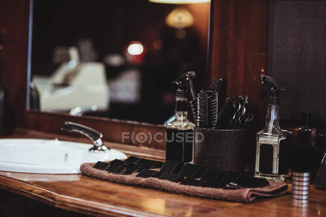 Garrafas de spray de barbeiro, escova e acessórios na mesa de vestir na barbearia — Fotografia de Stock