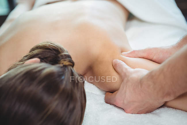 Physiotherapist giving physical therapy to shoulder of female patient in clinic — Stock Photo