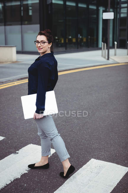 Ganzkörperporträt einer lächelnden Geschäftsfrau mit Laptop unterwegs — Stockfoto