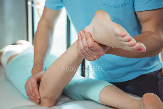 Immagine ritagliata del fisioterapista che somministra fisioterapia alla gamba della paziente in clinica — Foto stock