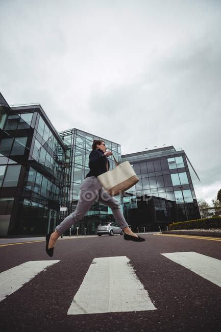 Businesswoman running by office building on road — Stock Photo