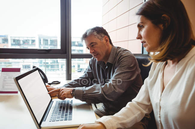 Mulher discutindo com colega sobre laptop no escritório — Fotografia de Stock