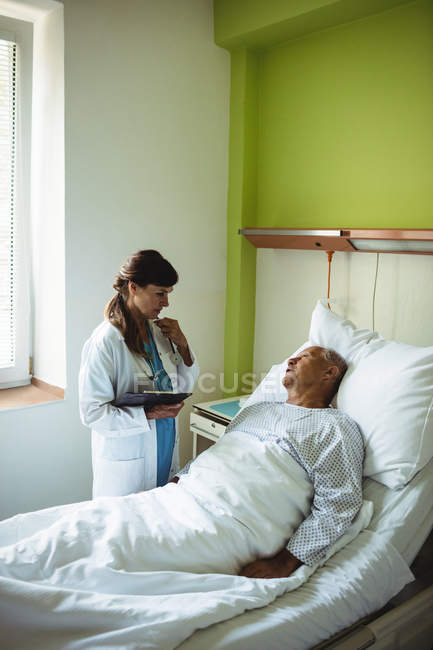 Женщина-врач взаимодействует со старшим мужчиной в больнице — стоковое фото