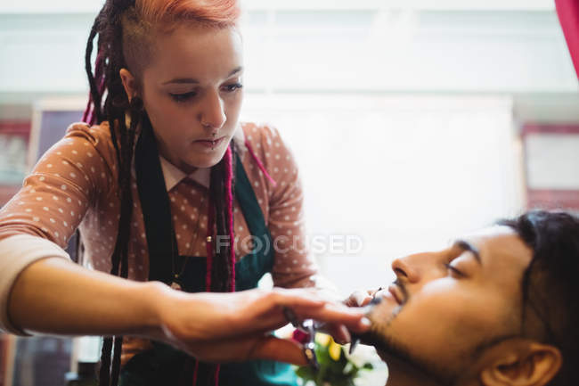 Man getting his beard trimmed with scissor in barber shop — Stock Photo