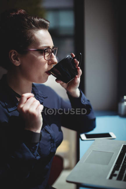 Молода жінка п'є каву в кафе — стокове фото