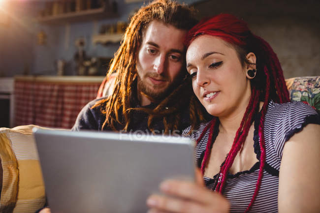 Молодая пара хипстеров с помощью цифрового планшета, сидя дома — стоковое фото